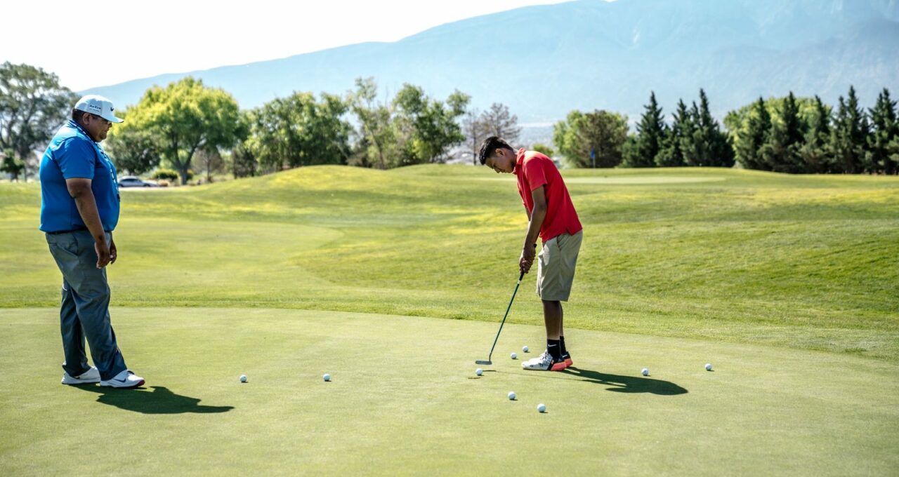 Deux joueurs s'entraînent au putting sur un green d'entraînement.