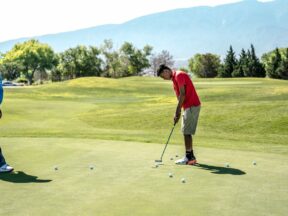 Deux joueurs s'entraînent au putting sur un green d'entraînement.