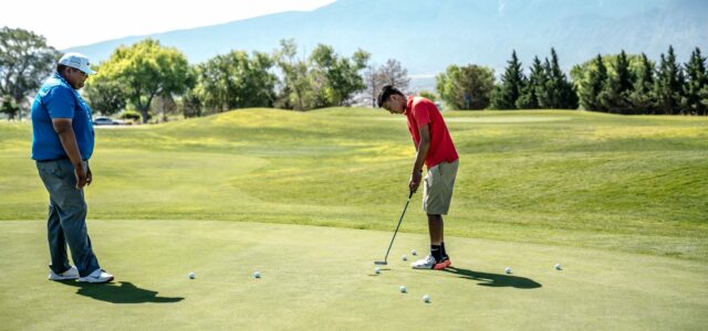 Deux joueurs s'entraînent au putting sur un green d'entraînement.