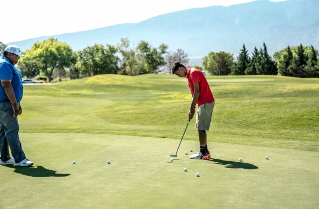Deux joueurs s'entraînent au putting sur un green d'entraînement.