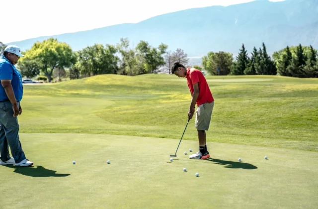 Deux joueurs s'entraînent au putting sur un green d'entraînement.