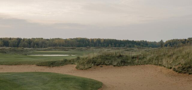 Fairway de links bordé de dunes de sable et d'herbes hautes.