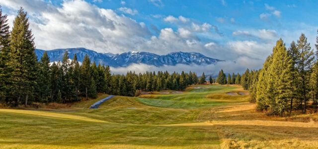 Parcours de golf de montagne, sommets enneigés et pins en arrière-plan.