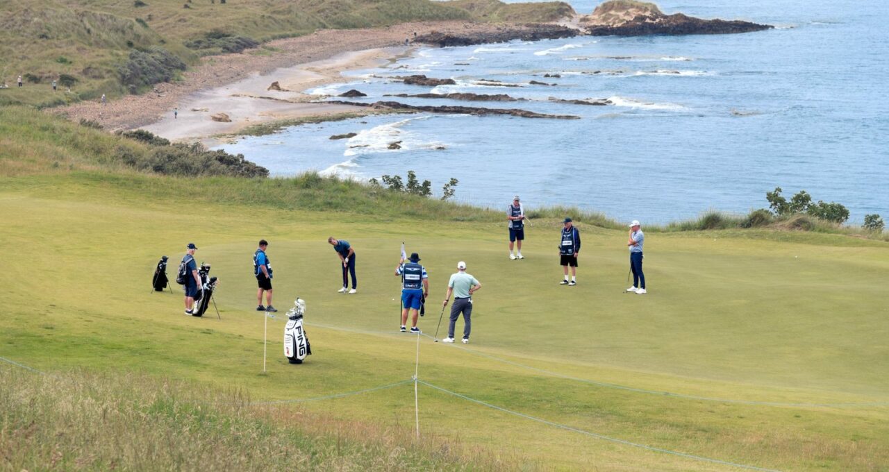 Green en bord de mer, joueurs et sacs rassemblés autour du drapeau.