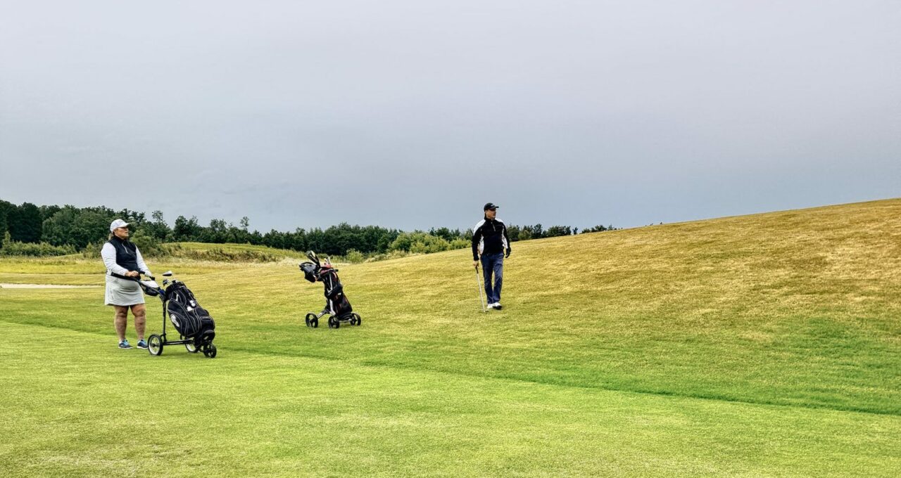 Joueurs et chariots sur un fairway un jour de forte affluence.