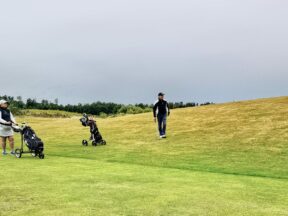 Joueurs et chariots sur un fairway un jour de forte affluence.