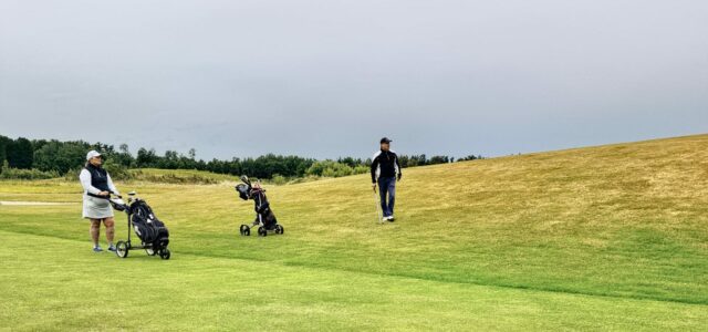 Joueurs et chariots sur un fairway un jour de forte affluence.