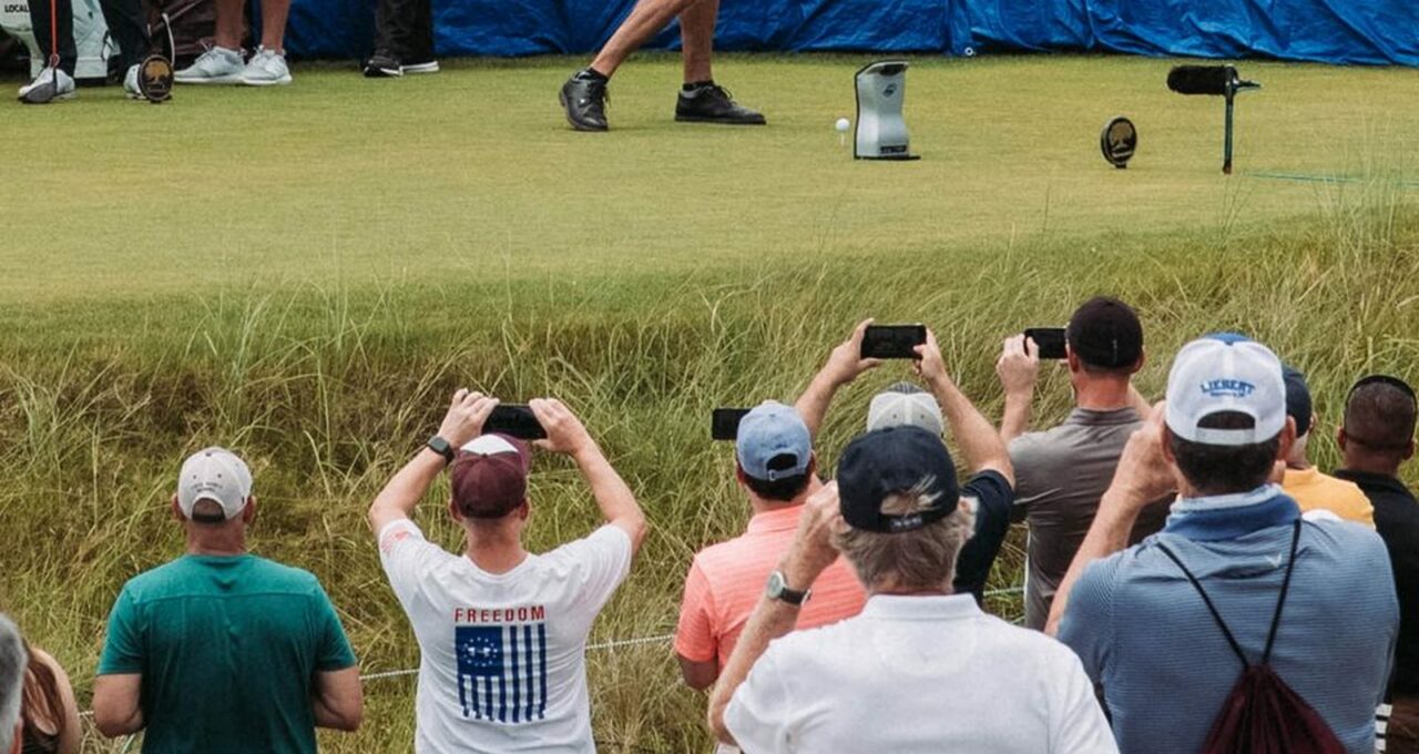 Des spectateurs filment un joueur au départ, derrière la corde.