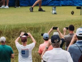 Des spectateurs filment un joueur au départ, derrière la corde.