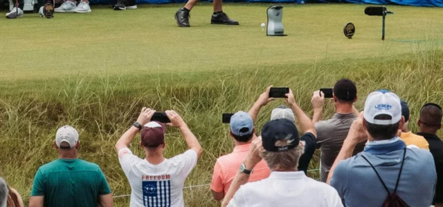 Des spectateurs filment un joueur au départ, derrière la corde.