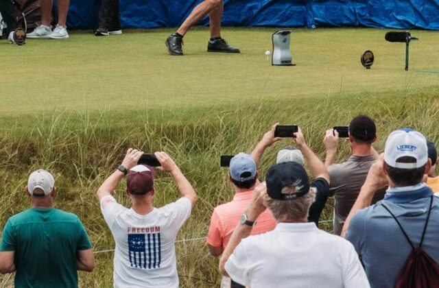 Des spectateurs filment un joueur au départ, derrière la corde.