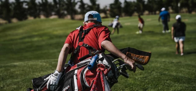 Golfer carrying a bag towards the tee