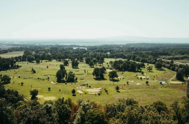 Golfbaan van bovenaf, greens, bunkers en vijvers tussen de bomen