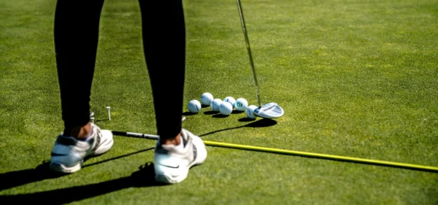 Golf shoes and balls lined up on the grass