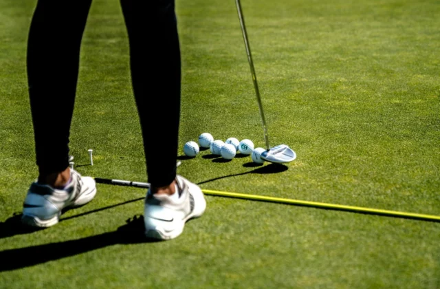 Golf shoes and balls lined up on the grass