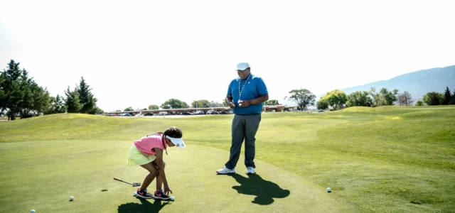 Enseignant de golf et jeune élève sur un green