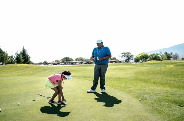 Enseignant de golf et jeune élève sur un green