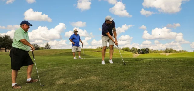 Vier golfers op een green onder een heldere hemel