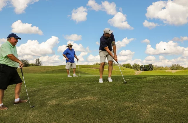 Four golfers on a green under a clear sky