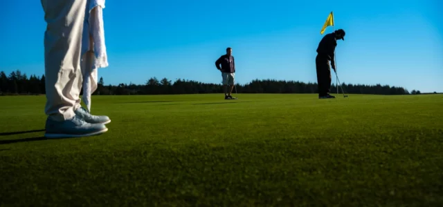 Golfeurs sur un green, l'un en position de putt