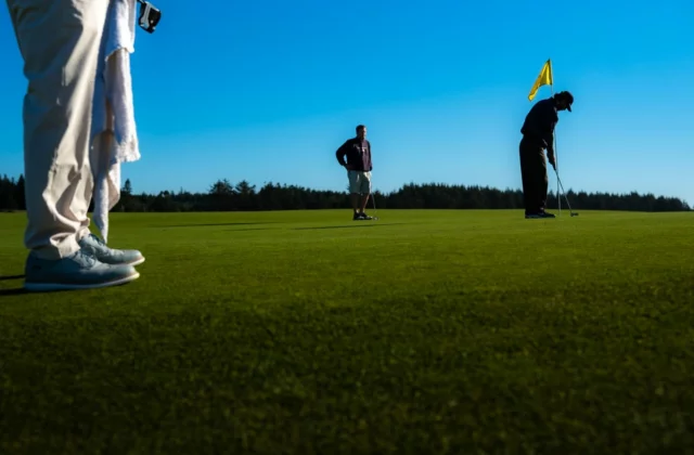 Golfeurs sur un green, l'un en position de putt