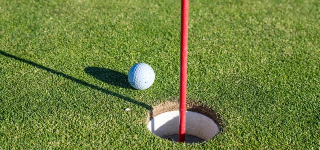 Golf ball on the lip of the hole, flag tilted