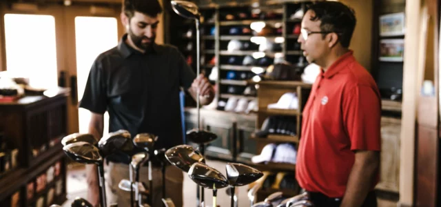 Two customers at a rack of clubs in a shop