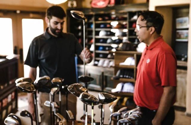 Two customers at a rack of clubs in a shop