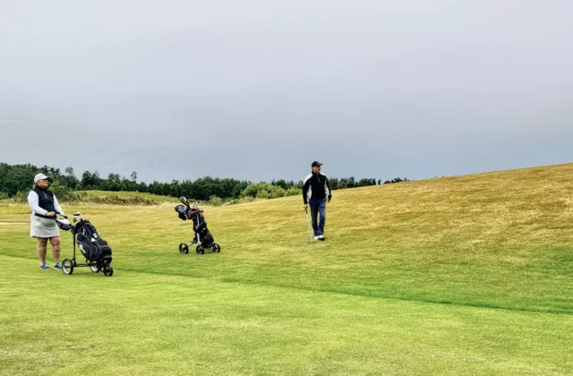 Golfeurs et chariots sur un fairway vallonné