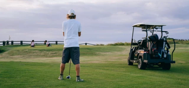 Lone golfer on the tee, cart behind