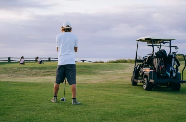 Lone golfer on the tee, cart behind