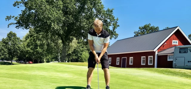 Golfer putting in front of a clubhouse