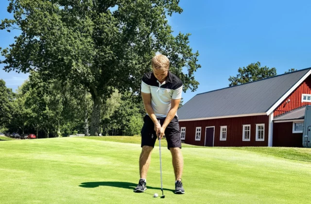 Golfer putting in front of a clubhouse