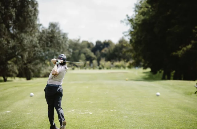 Golfer mid-swing seen from the fairway