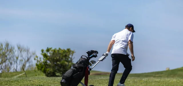 Golfer pushing a trolley on the course