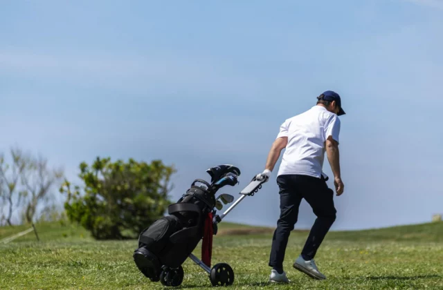 Golfer pushing a trolley on the course