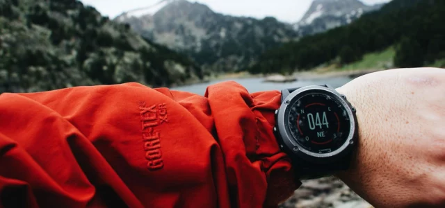 Golf GPS watch on a wrist, course behind
