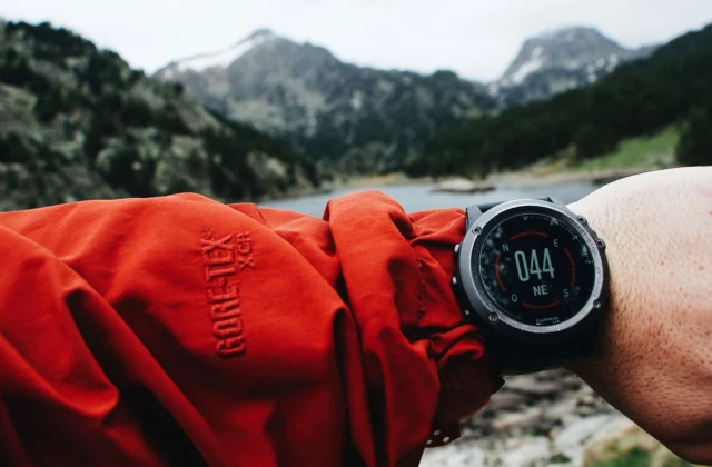 Golf GPS watch on a wrist, course behind