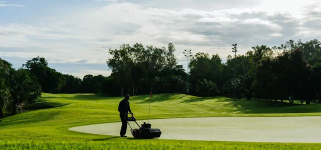 Greenkeeper mowing a green