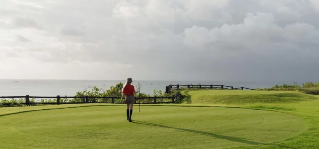 Golferin auf einem freiliegenden Grün über dem Meer