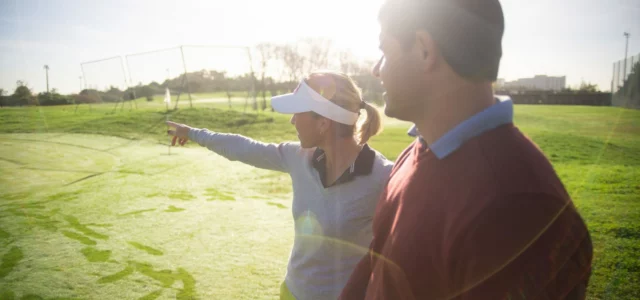Zwei Golfer auf der Range, einer zeigt aufs Ziel