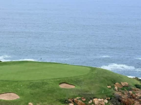 A clifftop green guarded by two bunkers, above the ocean