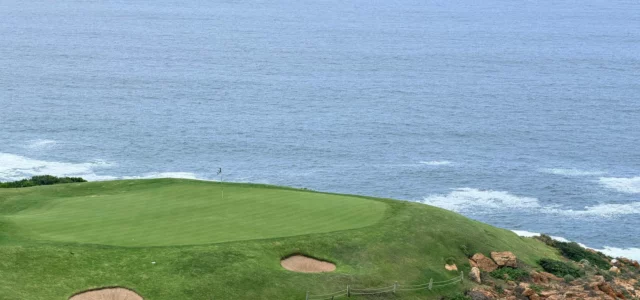 A clifftop green guarded by two bunkers, above the ocean